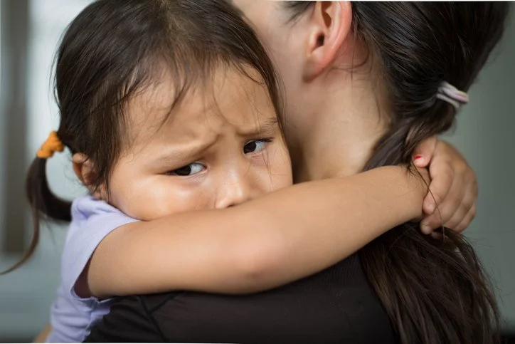 Toddler crying while being comforted with a hug