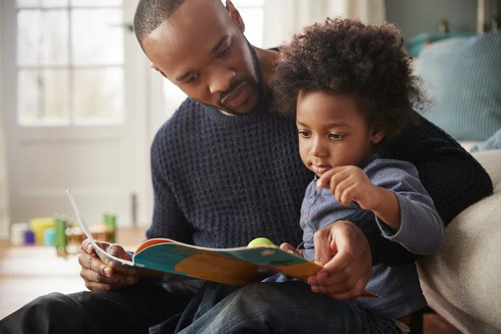 Parent reading a picture book together with a child on their lap