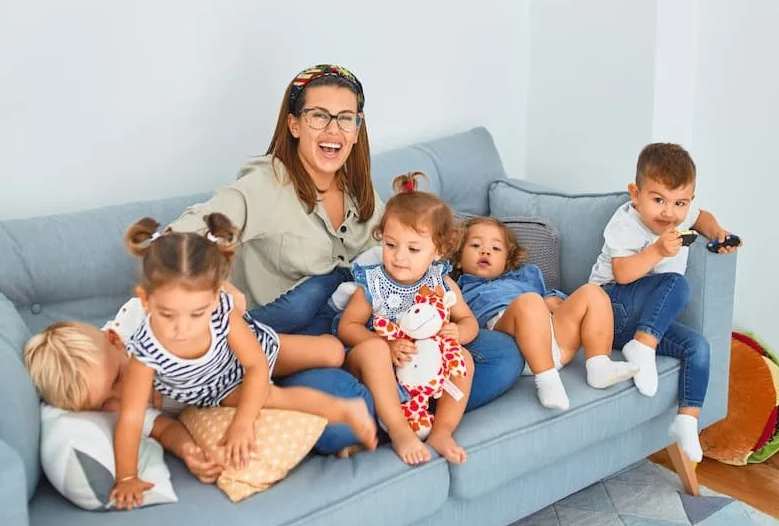 Mother sitting on a couch surrounded by four young children