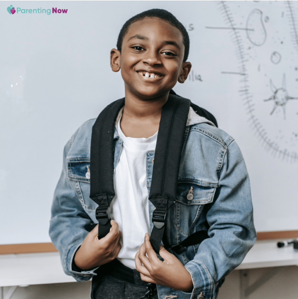 Smiling elementary school boy wearing a backpack in a classroom