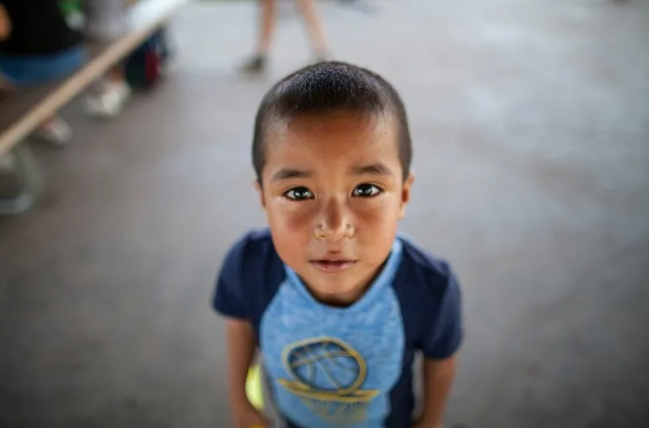 Young boy looking at the camera during an outdoor community gathering