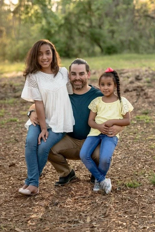 Two parents and their daughter smiling together outdoors
