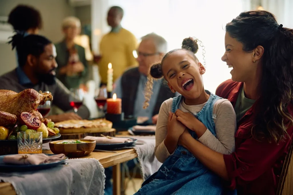 Family gathered around a holiday dinner table with a joyful child