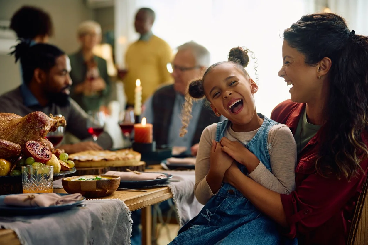 Family gathered around a holiday dinner table with a joyful child