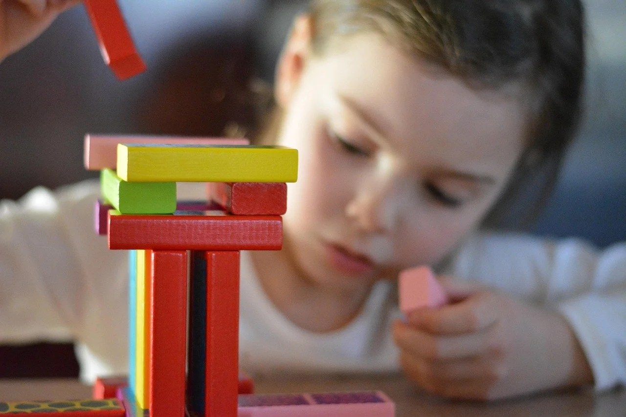 Girl stacking a tower of colorful wooden blocks