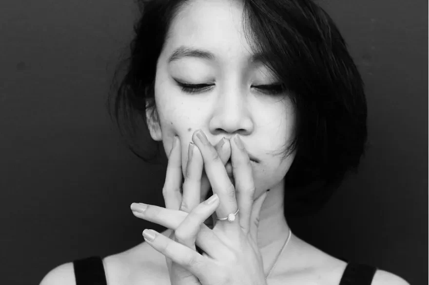 Woman with eyes closed appearing exhausted, hand near her face