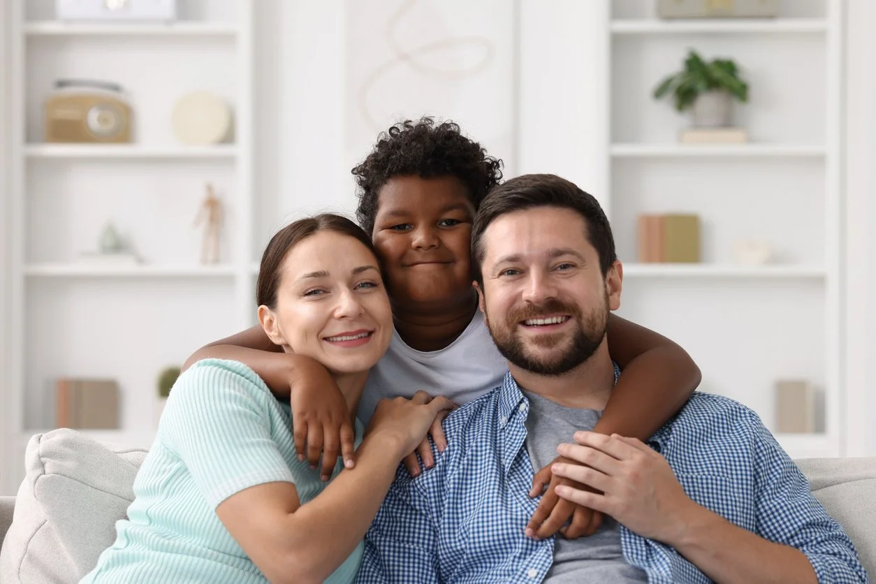 Family embracing and smiling together on the couch at home
