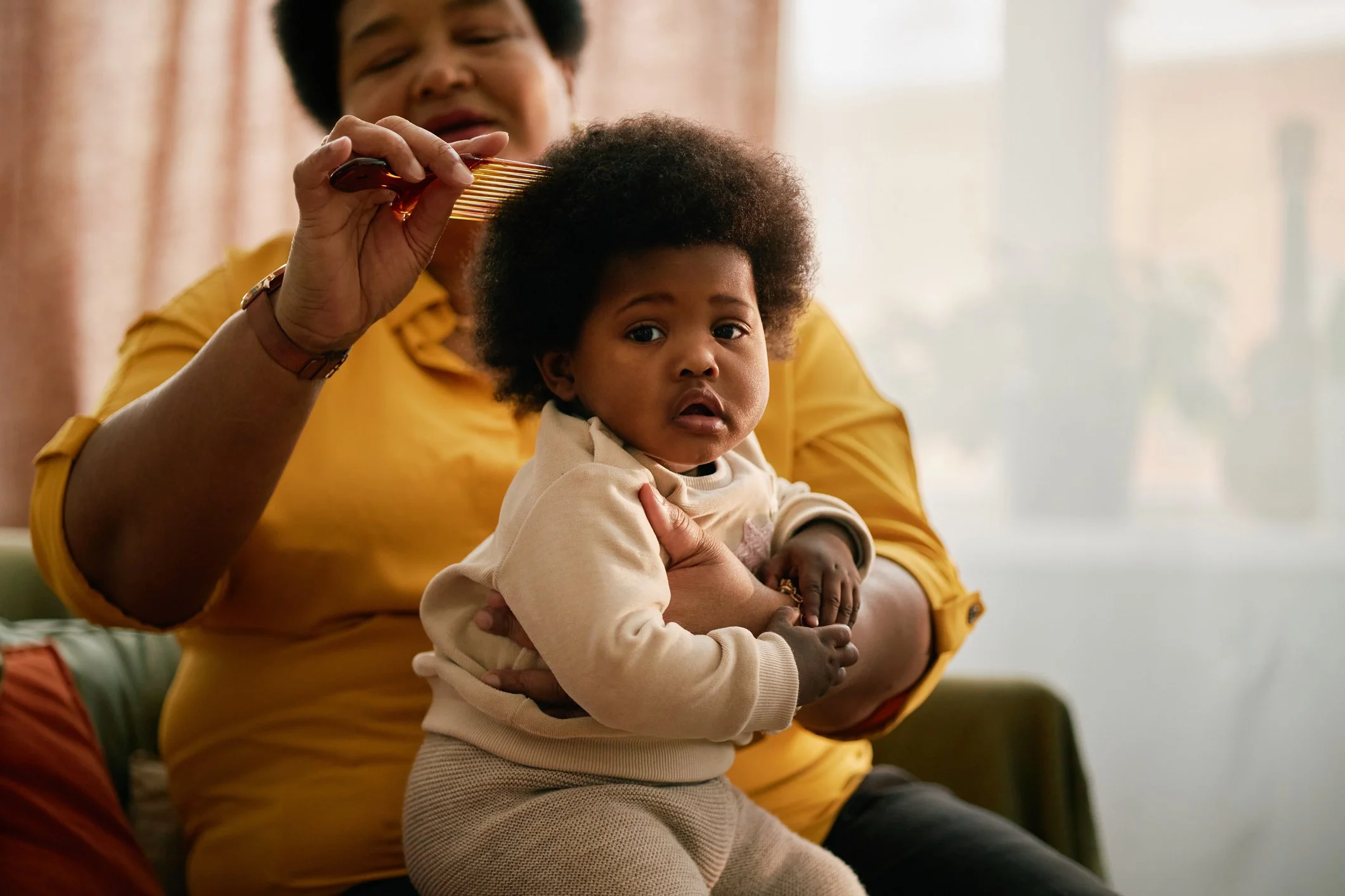 Woman carefully styling a baby's curly hair at home