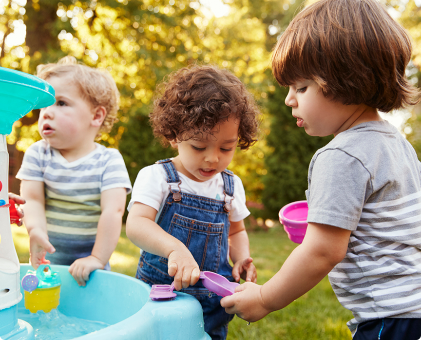 Toddlers playing together at an outdoor water play table