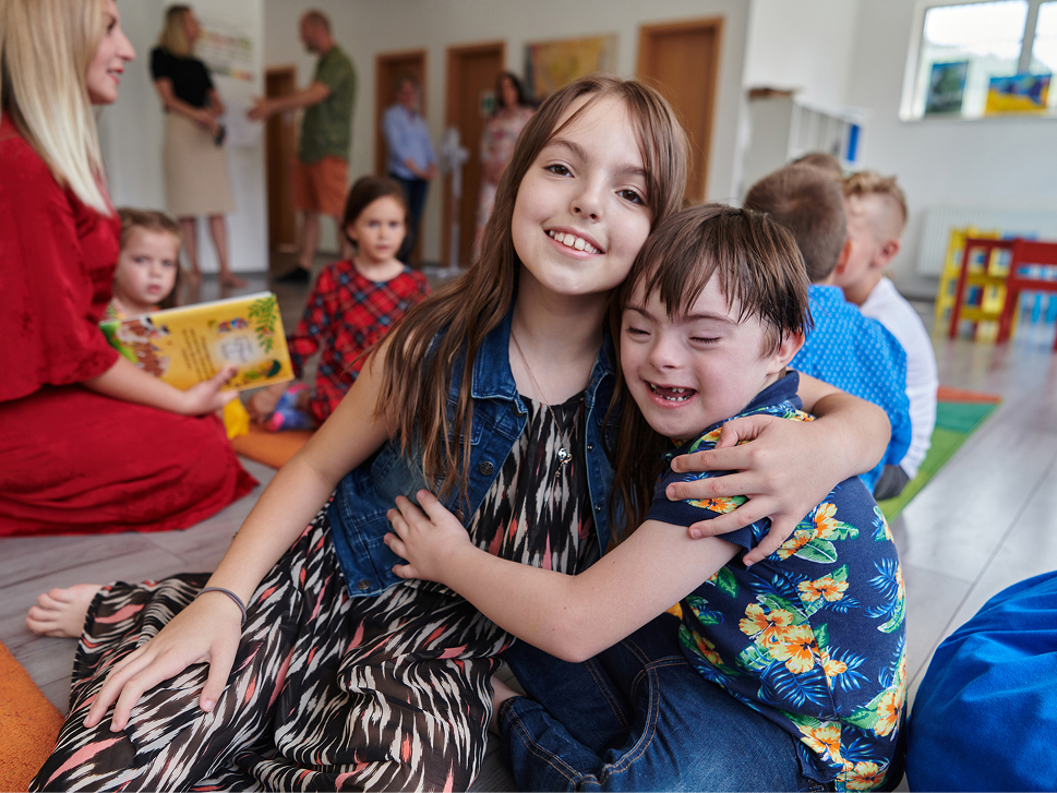Two children hugging and laughing together during classroom playtime