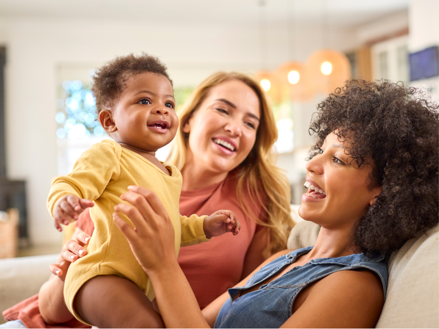 Two adults sharing a joyful moment with a baby